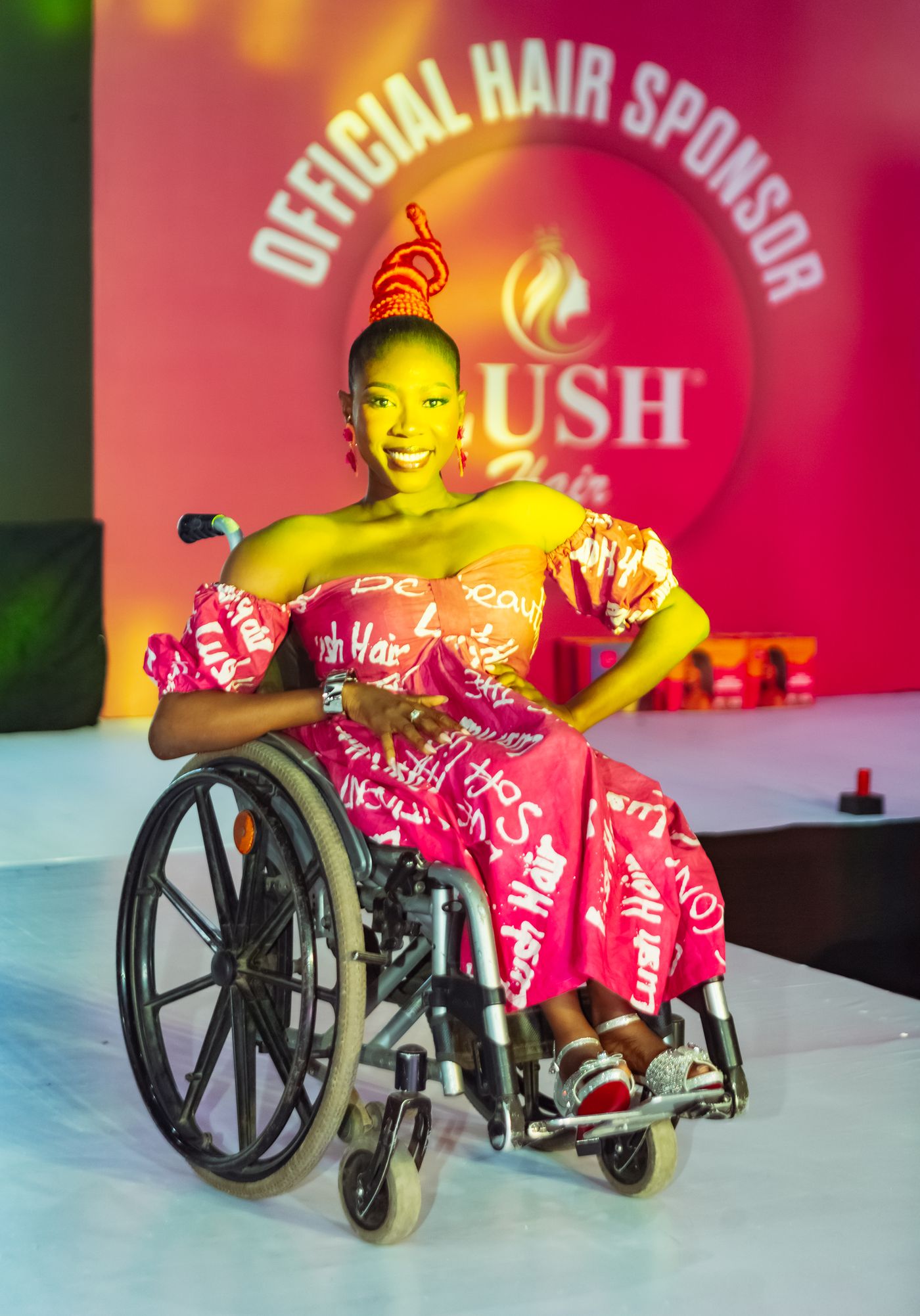A model in a wheelchair wearing a Lush Hair sponsored gown on the runway